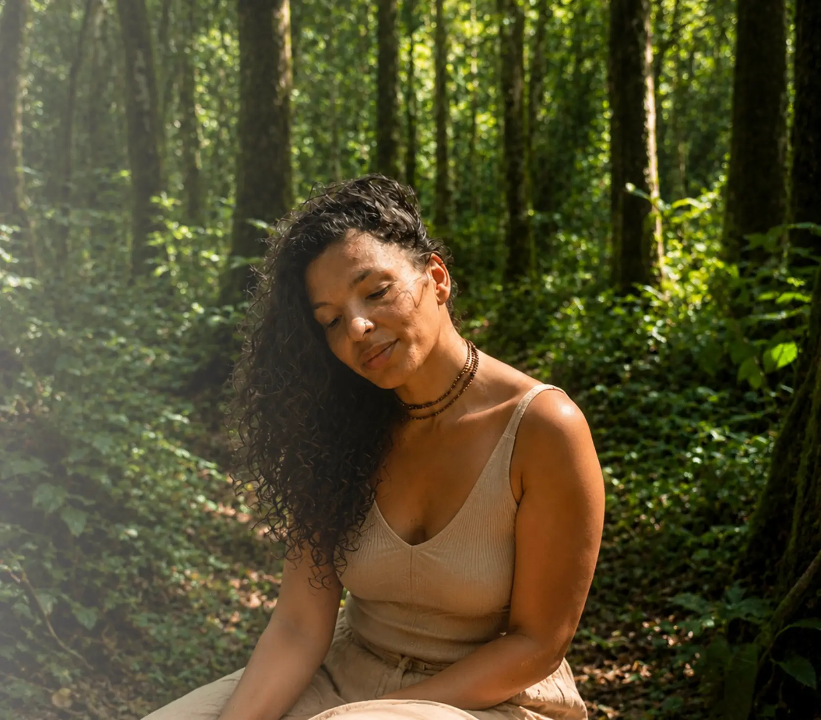 Laura sentada em uma floresta, em silêncio, sob luz quente